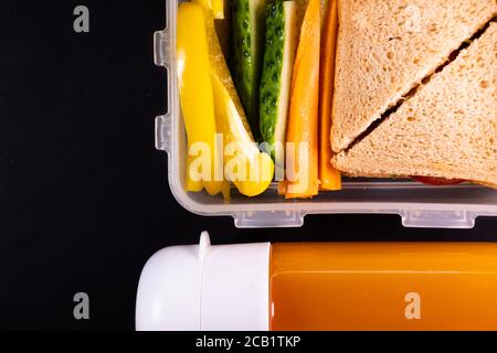Sandwich au pain et légumes dans une boîte à lunch à côté d'une bouteille de jus - vue du dessus et espace de copie. Déjeuner sain, repas à base de plantes ou repas végétarien Banque D'Images