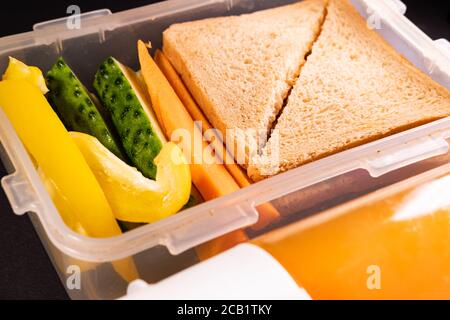 Sandwich au pain et légumes dans une boîte à lunch à côté d'une bouteille de jus. Déjeuner sain, déjeuner à base de plantes ou déjeuner scolaire végétarien Banque D'Images
