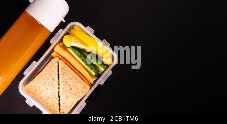 Sandwich au pain et légumes dans une boîte à lunch à côté d'une bouteille de jus - vue du dessus et espace de copie. Déjeuner sain, repas à base de plantes ou repas végétarien Banque D'Images