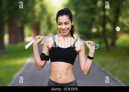 Entraînement cardio en plein air. Positive Asian Girl tenant corde à sauter Banque D'Images