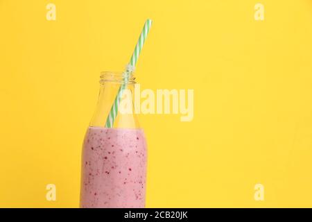 Smoothie BlackBerry dans une bouteille en verre avec une paille il est isolé sur fond jaune Banque D'Images