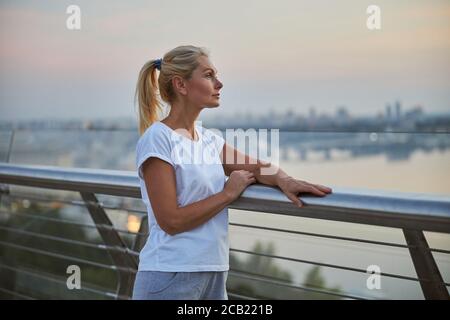 Femme sportive pensive s'appuyant sur la main courante Banque D'Images
