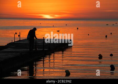 silhouette de pêcheur près de la mer au lever du soleil. Routine quotidienne de pêcheur. Lever du soleil à Marsascala, Malte Banque D'Images