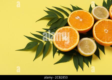 Composition des moitiés de citrons et d'oranges avec feuilles vertes sur fond jaune vif Banque D'Images