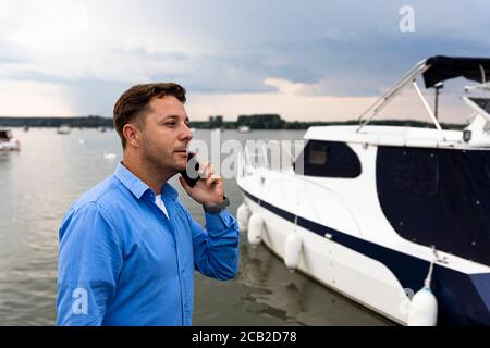 Homme parlant au téléphone à côté du yacht de luxe au port. Concept marin et marin Banque D'Images