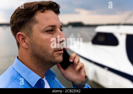 Homme parlant au téléphone à côté du yacht de luxe au port. Concept marin et marin Banque D'Images