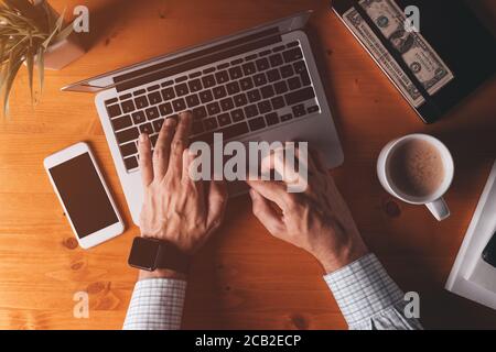 Homme d'affaires dactylographiant ordinateur portable clavier, vue aérienne de bureau le matin Banque D'Images