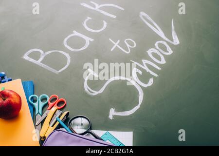concentration sélective des fournitures scolaires et de la pomme fraîche près du dos au lettrage scolaire sur le tableau vert Banque D'Images