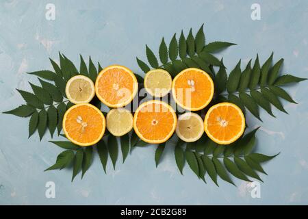 Composition de moitiés de citrons et d'oranges avec feuilles vertes sur fond bleu clair, Flat Lay Banque D'Images