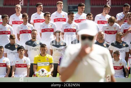 10 août 2020, Bade-Wurtemberg, Stuttgart: Football, Bundesliga: VfB Stuttgart - séance photo, séance photo officielle de l'équipe de Stuttgart (photos d'équipe et portraits) pour la saison 2020/2021 dans l'arène Mercedes-Benz. Un homme avec un masque de protection et des lunettes de soleil marche devant l'équipe. Photo: Marijan Murat/dpa - NOTE IMPORTANTE: Conformément aux règlements de la DFL Deutsche Fußball Liga et de la DFB Deutscher Fußball-Bund, il est interdit d'exploiter ou d'exploiter dans le stade et/ou à partir du jeu pris des photos sous forme d'images de séquence et/ou de photo de type vidéo Banque D'Images