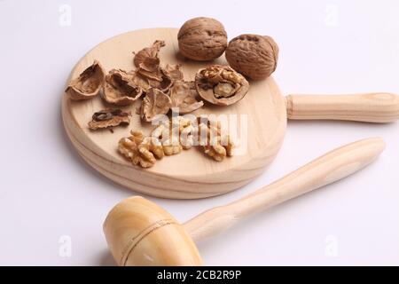 Tir à grand angle de noix et de coquilles écrasées sur un planche à découper à côté d'un petit marteau en bois Banque D'Images