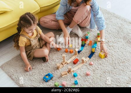 vue rognée de nounou à côté d'un adorable enfant jouant avec multicolore blocs Banque D'Images