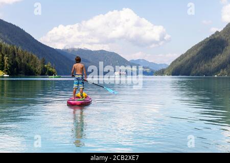 Young boy sur paddleboard sur le lac Banque D'Images