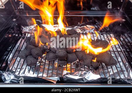 Flammes sur un barbecue qui a été allumé jus. Le charbon de bois brûle avant de se tourner vers les Embers prêts à cuire. Banque D'Images