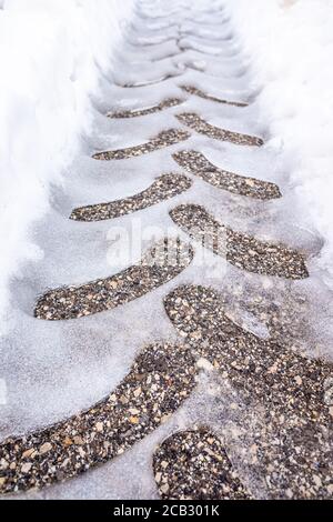 Détail des traces d'une roue sur l'asphalte enneigé, vu d'en haut. Banque D'Images