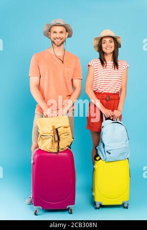 couple heureux en chapeaux debout avec bagages et sacs à dos bleu Banque D'Images