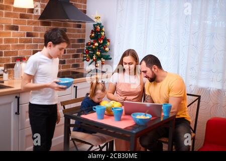 un concept familial sympa. une famille charmante s'assoit ensemble dans la cuisine pour prendre le repas, prendre le petit déjeuner, mère père et enfant garçon dans des vêtements décontractés Banque D'Images