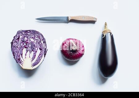 déposer à plat avec un couteau, un oignon rouge, un chou rouge, une aubergine sur fond blanc Banque D'Images