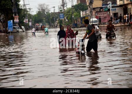 Les Pakistanais sont sur leur chemin le long d'une route inondée alors qu'ils sortaient de leurs maisons tandis que leurs maisons ont été inondées d'eau d'inondation après une forte vague de pluies de mousson sur le plan chinois à Lahore le 09 août 2020.selon le ministère met, De fortes pluies de mousson ont été écrasées à Lahore et dans ses zones voisines au petit matin du dimanche. La pluie incessante a inondé les routes et les rues dans de nombreuses parties de la ville, de l'eau de pluie est entrée dans des maisons dans plusieurs zones basses de Lahore tandis que certaines parties de la ville ont été témoins d'une coupure de courant, plus de 150 000 nourrisseurs Lesco ont trébuché peu après le début de la pluie. (Photo Banque D'Images