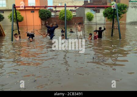 Les Pakistanais sont sur leur chemin le long d'une route inondée alors qu'ils sortaient de leurs maisons tandis que leurs maisons ont été inondées d'eau d'inondation après une forte vague de pluies de mousson sur le plan chinois à Lahore le 09 août 2020.selon le ministère met, De fortes pluies de mousson ont été écrasées à Lahore et dans ses zones voisines au petit matin du dimanche. La pluie incessante a inondé les routes et les rues dans de nombreuses parties de la ville, de l'eau de pluie est entrée dans des maisons dans plusieurs zones basses de Lahore tandis que certaines parties de la ville ont été témoins d'une coupure de courant, plus de 150 000 nourrisseurs Lesco ont trébuché peu après le début de la pluie. (Photo Banque D'Images