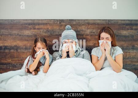 famille caucasienne malade, couchée au lit ensemble, souffrant de maladie. Un homme, une femme et une fille malsains se traitant à la maison Banque D'Images