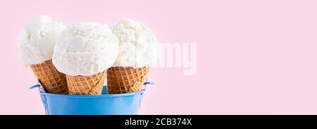 Cornets de crème glacée dans un seau bleu sur fond rose. Un cône de glace de type cachets. Longue bannière Banque D'Images