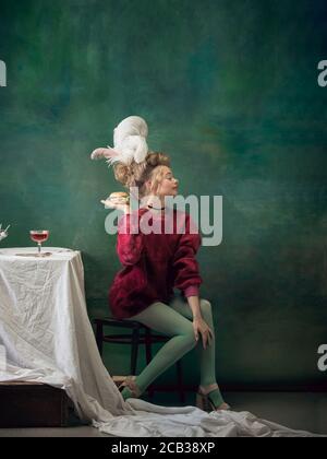 Burger Queen. Jeune femme comme Marie-Antoinette isolée sur fond vert foncé. Style rétro, comparaison du concept ERAS. Magnifique mannequin comme un personnage historique classique, à l'ancienne. Banque D'Images