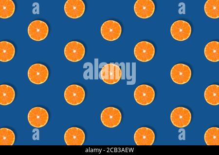 Motif de fruits de tranches d'agrumes d'orange vif fraîches isolées sur fond bleu classique. Flat lay, vue de dessus. Pop art design, couleur créative du 2020 Banque D'Images
