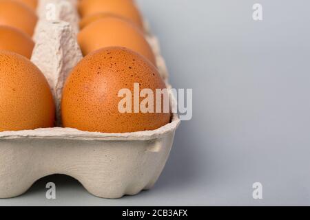 Vue rapprochée des œufs de poulet crus dans un œuf sur fond gris Banque D'Images