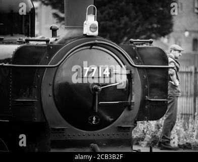 Gros plan monochrome de la locomotive à vapeur britannique d'époque, debout sur une plate-forme, Severn Valley Railway Kidderminster, avec chauffeur de train à vapeur en attente. Banque D'Images