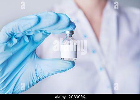 Infirmière ou médecin détenant un vaccin, un médicament. Main dans un gant bleu Banque D'Images