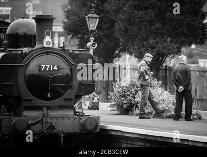 Vue en noir et blanc de l'équipe de locomotive à vapeur du Royaume-Uni qui attend sur la plate-forme de la gare, Severn Valley Railway, Kidderminster, Worcestershire. Banque D'Images