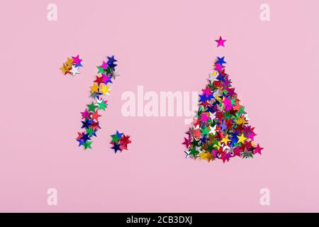 Un symbole de réduction et un arbre de noël avec des étoiles multicolores sur fond rose. Une affiche de pourcentage, ventes de noël Banque D'Images