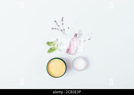 Composition Flat Lay cosmétiques naturels de soins de la peau, crème hydratante, masque facial et sérum en flacon avec pipette à côté de fleurs de lavande et de lea vert Banque D'Images