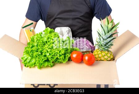 Homme tenant une boîte de carton avec de la laitue, de la tomate et des spaghetti, ananas isolé sur blanc. Banque D'Images