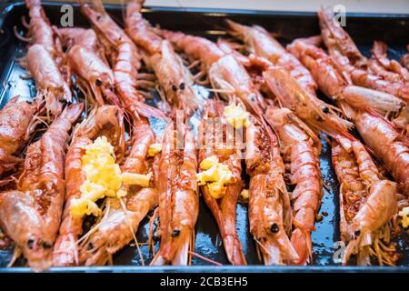 Un plateau de grosses crevettes géantes en noir et blanc et monochrome. Ils sont préparés dans du beurre à l'ail pour griller et dévorer. Crevettes déveinées, un BLOB de beurre à l'ail, et fraîchement préparé. Banque D'Images