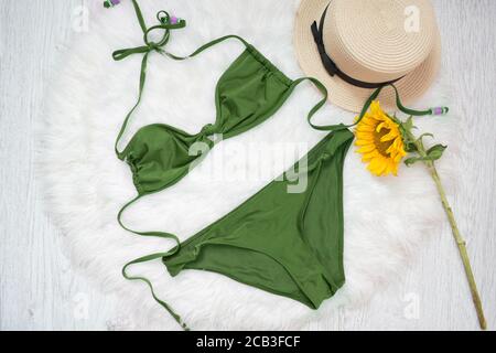 Maillot de bain vert, chapeau de paille et tournesol. Fourrure blanche sur l'arrière-plan, vue du dessus Banque D'Images