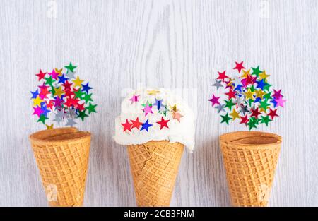 Des cônes de glace sont décorés d'étoiles sur un fond de bois blanc. Un cône de glace de type cachets. Heure d'été. Banque D'Images