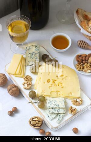 Apéritifs de différents types de fromage, raisins, noix et miel, servi avec des vins blanc et rouge. Style rustique. Banque D'Images