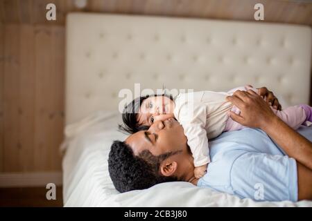 beau homme émotionnel embrassant sa fille en étant allongé dans la chambre à coucher, gros plan vue sur le côté photo, sensation tendre Banque D'Images