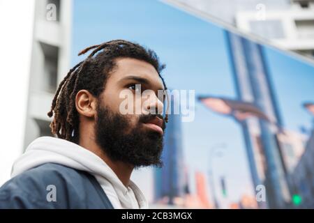 Image d'un beau jeune homme sérieux marchant à l'extérieur regardant de côté Banque D'Images