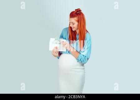Jeune femme élégante dans l'espérance ayant enveloppe avec l'argent pour bébé recherche heureux isolé sur fond bleu clair. J'ai reçu ma maternité de départ b Banque D'Images