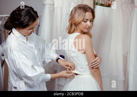 belle femme caucasienne client et tailleur dans la boutique de mariage, prenant des mesures du corps pour la création nouvelle robe, la préparation d'un mariage Banque D'Images