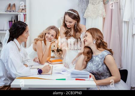 femme tailleur créateur de créer une nouvelle robe de mariage tendance et élégante avec de magnifiques jeunes filles caucasiennes, écoutez attentivement lui Banque D'Images