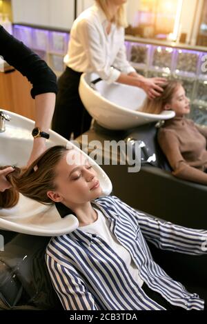 lavage et teinture des cheveux dans le salon de beauté, stylistes professionnels faisant leur travail quotidien. Jeune femme d'apparence caucasienne couché sur un bureau spécial pour Banque D'Images