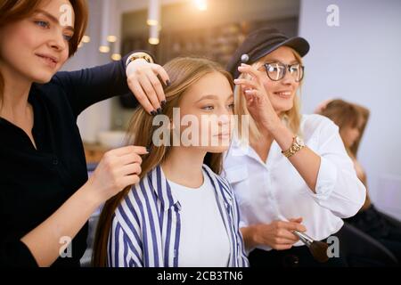 Coiffeur moderne et élégant tidies les cheveux longs du jeune client, en faisant une coiffure la veille des vacances. Transformation complète en salon de beauté Banque D'Images