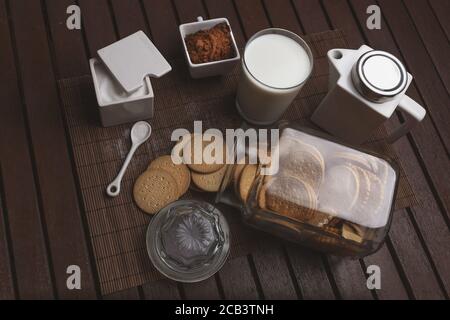 Table à café parfaitement conçue avec des biscuits croquants, une tasse de lait chaud et du café en poudre Banque D'Images