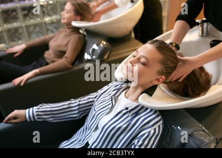 jeune et belle femme obtenant des procédures de beauté dans le saloon de coiffure, profiter et se détendre tout en étant allongé sur un lit spécial pour laver et teindre les cheveux dans le saloo Banque D'Images