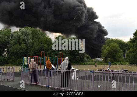Les gens observent les feux de fumée qui s'enveniment d'un incendie violent dans une zone industrielle de Birmingham, tandis que les équipages de 10 pompiers s'attaquent à l'incendie. Banque D'Images