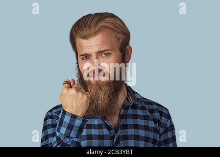 Homme donnant le pouce, le doigt, le geste de fig. vous obtenez zéro rien. Culotte taille basse avec barbe en chemise à carreaux bleus. Studio isolé bleu arrière-plan. NEG Banque D'Images